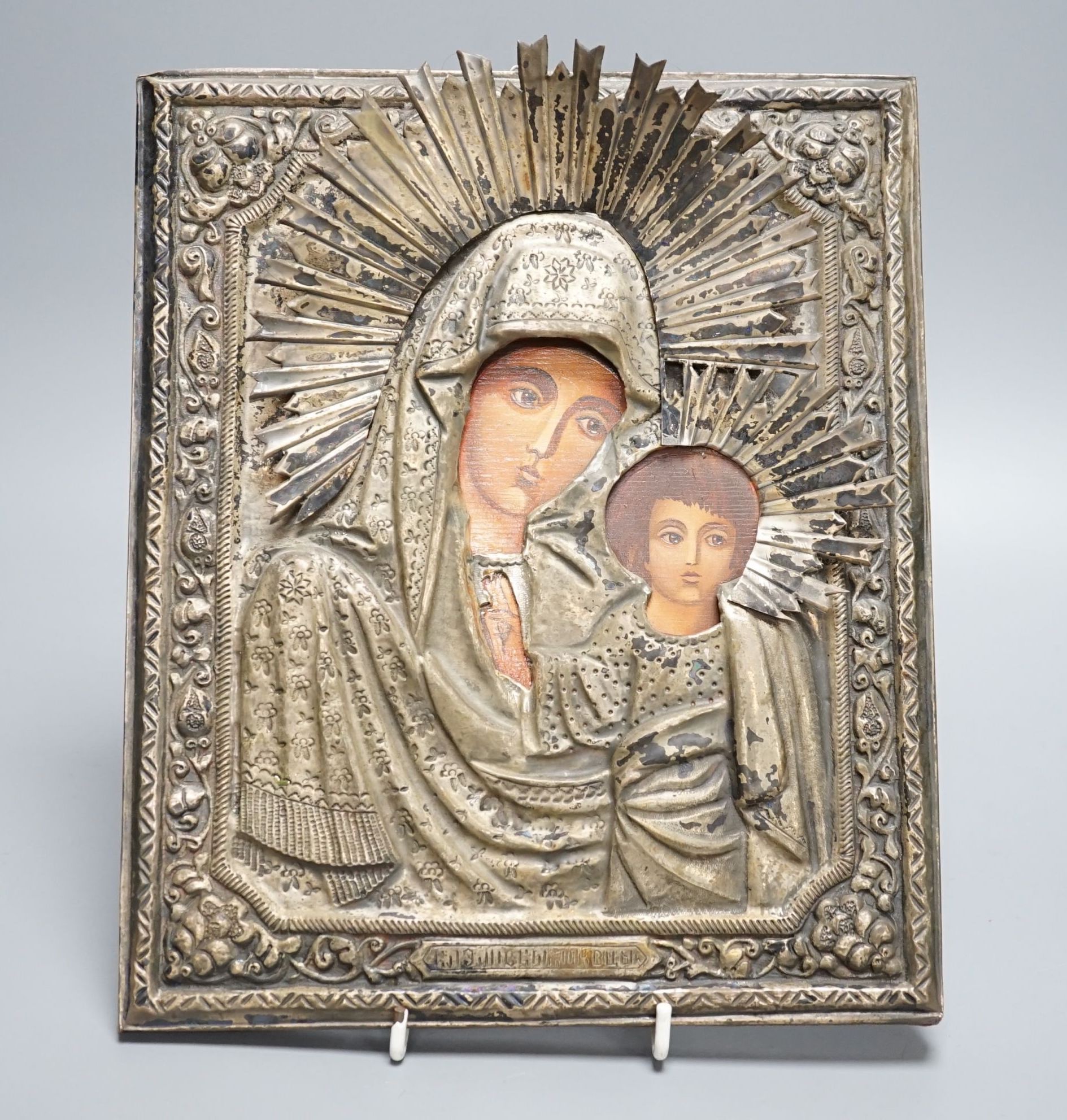 A Russian icon of Madonna and child, in embossed white metal frame, 27cm high